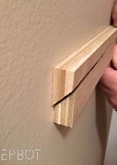 a person holding a piece of wood in their hand and pulling it up against the wall