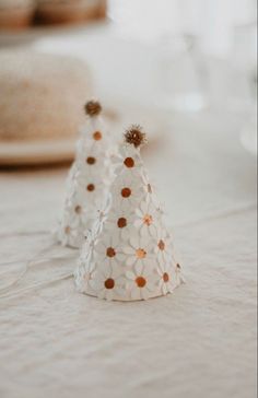 two small white paper hats sitting on top of a table next to plates and glasses