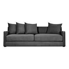 a gray couch with six pillows on it's back and one arm facing the camera