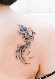 the back of a woman's shoulder with a bird tattoo on it