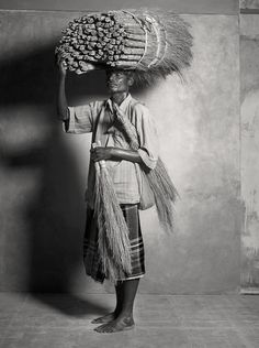 an old black and white photo of a man carrying something on his head