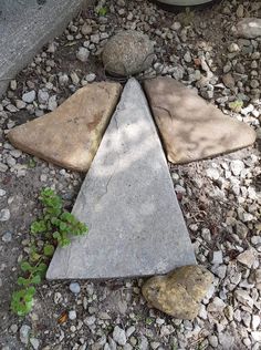 a triangle shaped rock sitting on top of a gravel ground