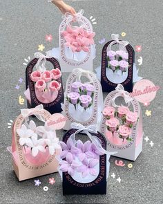 several small bags with flowers in them sitting on the ground next to a person's hand