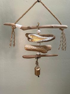 a wind chime hanging from a rope with beads and shells on it's sides