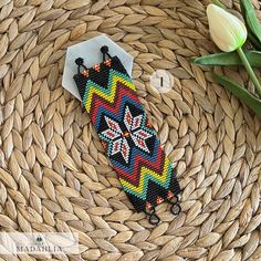 a beaded bracelet sitting on top of a woven table cloth next to tulips