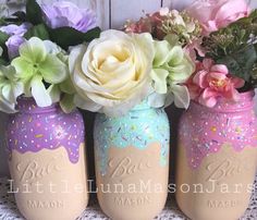 three painted mason jars with flowers in them