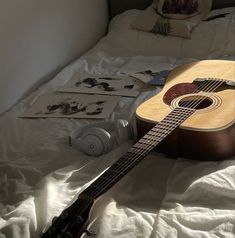 an acoustic guitar is laying on the bed