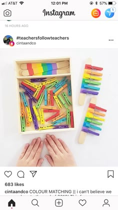 someone is holding their hands in front of a box full of colored matchsticks