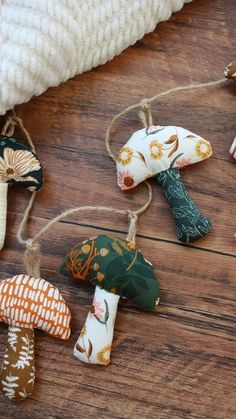 small mushrooms are hanging from twine strings on a wooden floor with white blanket and pillow in the background