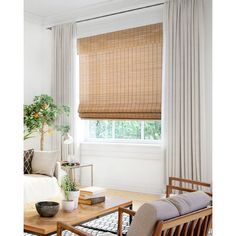 a living room with white walls and wooden blinds on the windowsills, along with a coffee table