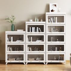 a white bookcase filled with lots of books on top of a hard wood floor