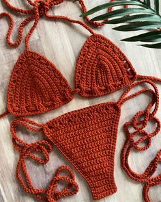 an orange crocheted bikinisuit with matching headbands on a wooden surface