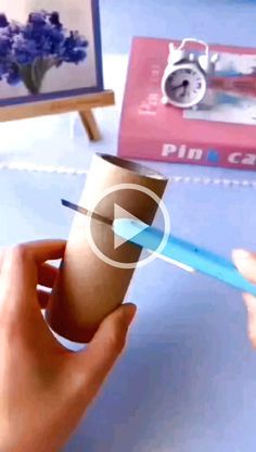 a person holding a cup with a toothbrush in it while another hand holds a pen