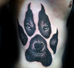 a dog's paw tattoo on the side of his chest is black and grey