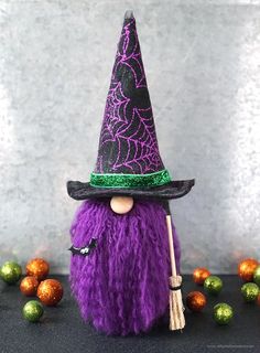 a purple and black witch doll with a broom