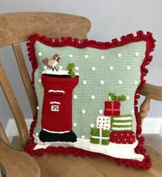 a christmas pillow sitting on top of a wooden chair next to a green cushion with red trim