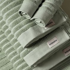 three folded green towels with labels on them