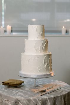 a three tiered white cake sitting on top of a table next to a knife