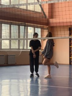 two people standing in an indoor volleyball court