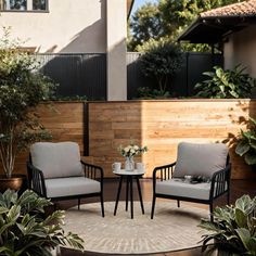 two chairs sitting on top of a rug next to a table and potted plants