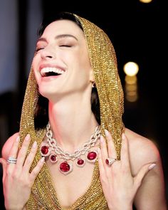 a woman wearing a gold veil and red jewels on her neck, smiling at the camera