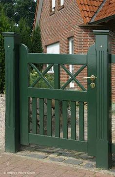 a green gate in front of a brick house