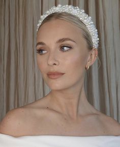 a woman wearing a white headband with pearls on it's side and her eyes closed