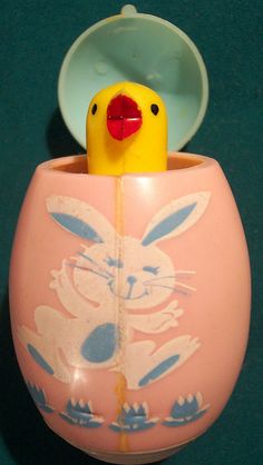 a yellow rubber duck in a pink ceramic cup with an easter bunny design on it