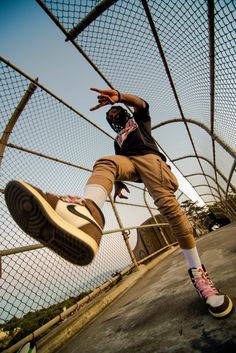 a person jumping in the air on a skateboard near a fence and some trees