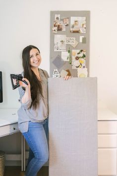 a woman standing behind a desk holding a camera