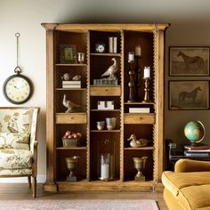 a living room filled with furniture next to a clock and wall mounted pictures on the wall