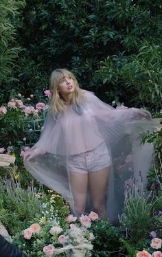 a woman standing in the middle of flowers