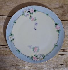 a white plate with pink and purple flowers on it sitting on a wooden table top