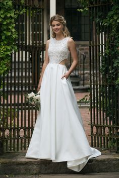 a woman standing in front of a gate wearing a wedding dress