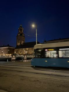 a blue bus driving down a street next to a tall building with a clock tower