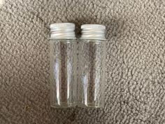 two empty glass bottles sitting on top of a carpet