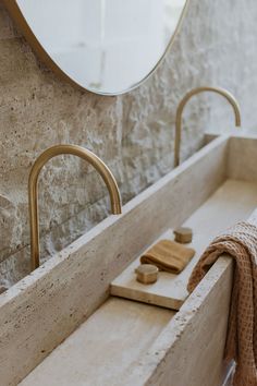 a bathroom sink with a wooden block on the counter and a round mirror above it