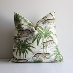 a pillow with leopards and palm trees printed on it, sitting on a table