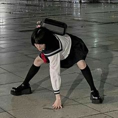 a woman in black and white is bending over on the ground with a suitcase on her head