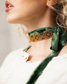 a close up of a woman wearing a green ribbon around her neck with beads on it