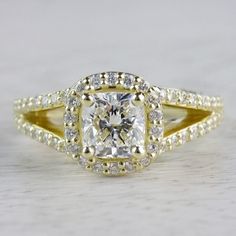 a yellow gold engagement ring with a square cut diamond surrounded by small round diamonds on the band