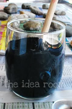 a glass filled with liquid sitting on top of a table next to rocks and spoons