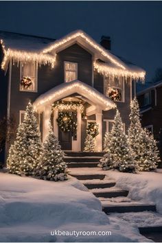 a house covered in christmas lights and decorated with garlands on the front door, trees and stairs