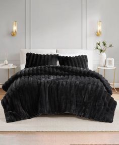 a bed with black fur on it in a room next to a white rug and wall