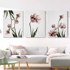 three floral paintings hanging on the wall in a living room