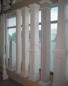 an orange circle is circled by white pillars in front of windows with blinds on them