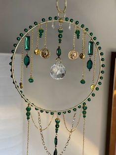 a green and gold necklace hanging from a hook on a white wall next to a mirror