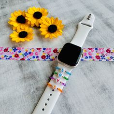 an apple watch sitting on top of a table next to sunflowers