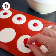 a person is pressing buttons on a red board with white dots and the word q above it