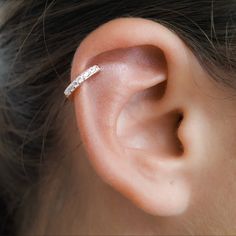 a woman's ear is shown with a single diamond bar in the middle of it